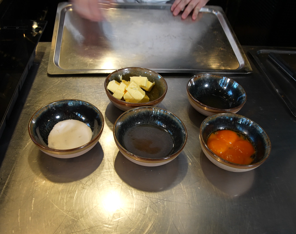 Fem skåler med forskjellige ingredienser, som eggeplommer, smør, reduksjon og salt. Foto.