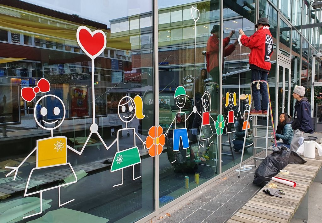 Fotografi av at tre elever monterer foliedekor på et vindu.