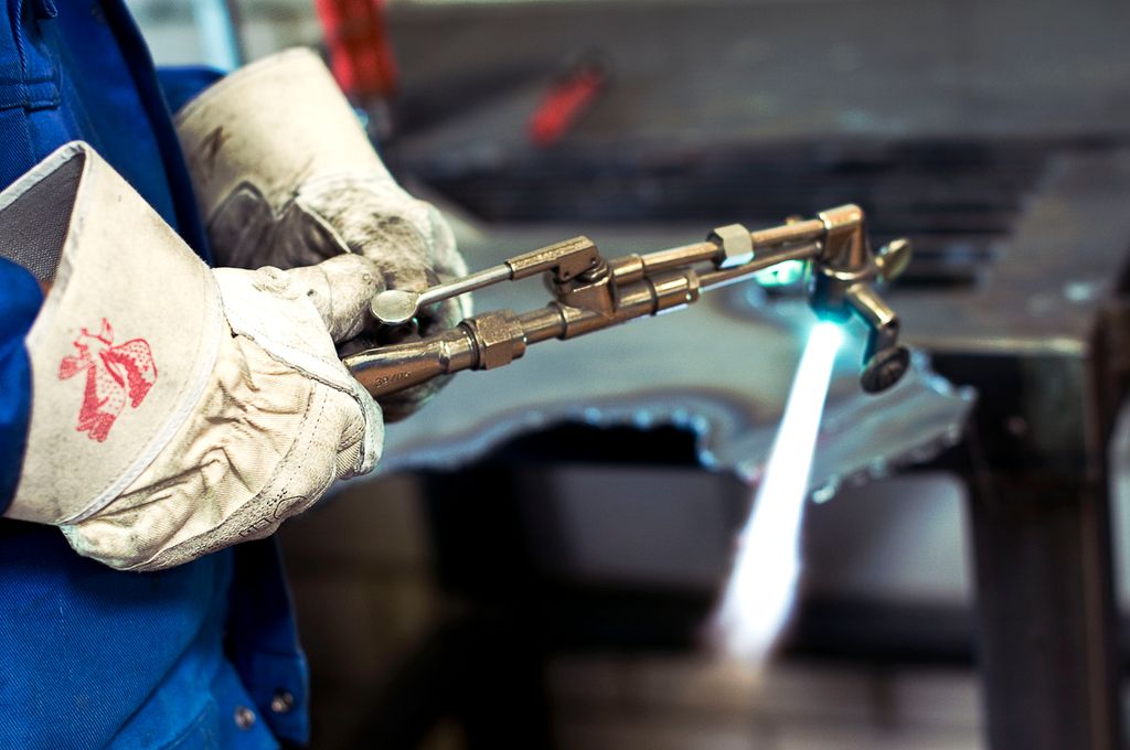 Person med hansker som holder en tent skjærebrenner med påmonterte løpehjul. Foto.