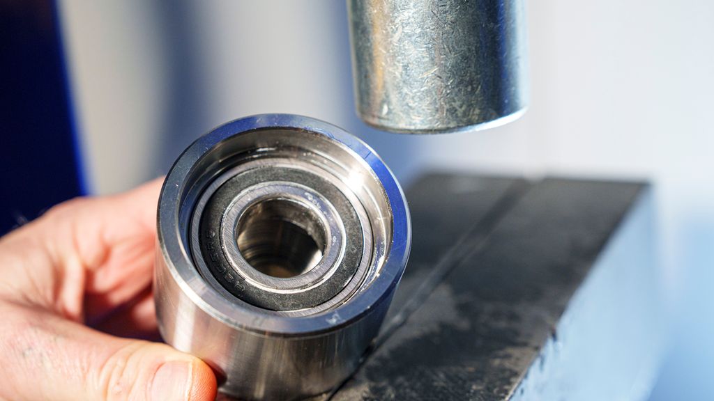 Hånd som holder to sylindriske deler. Foto.