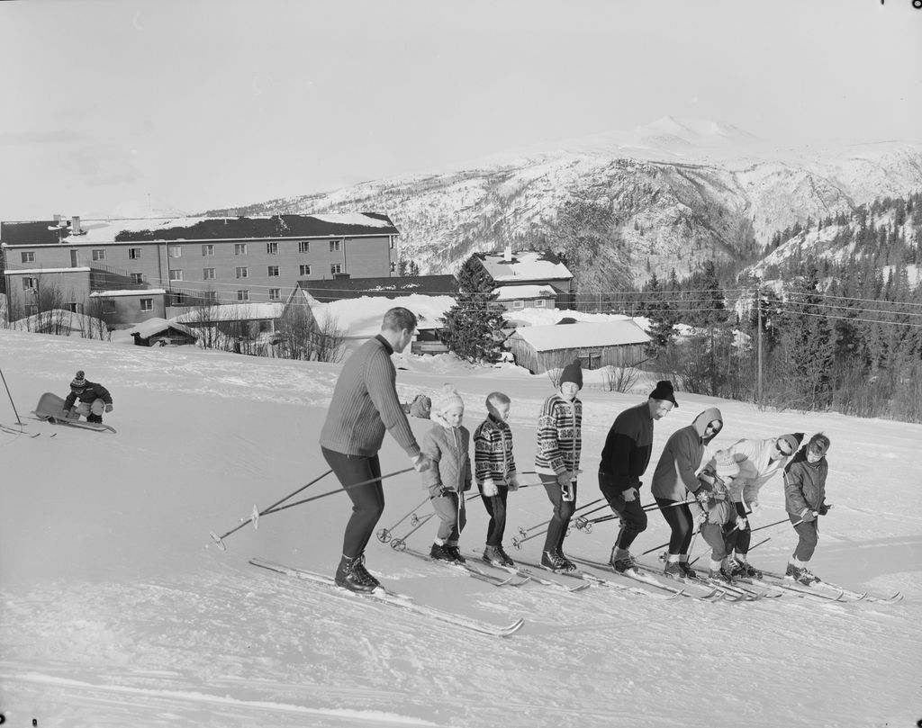 Vaksne og barn på ski i vinterlandskap. Foto.