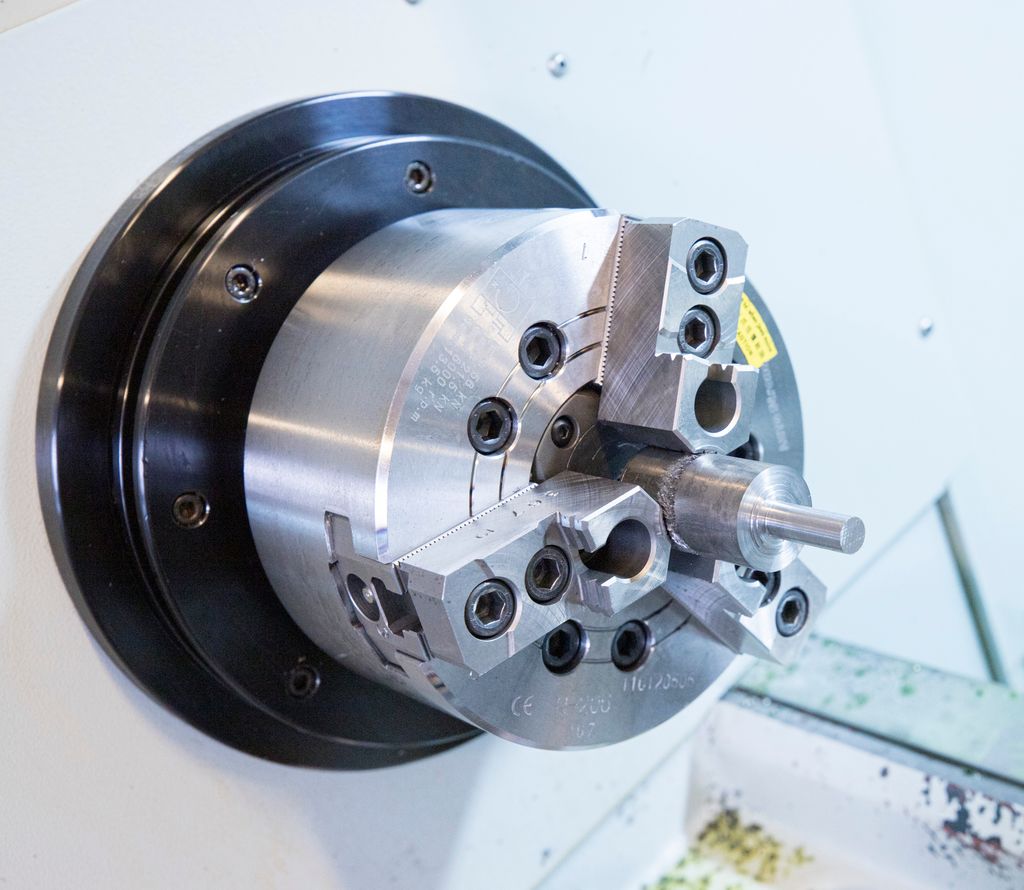 Kjoks med arbeidsemne oppspent i dreiebenk. Foto.