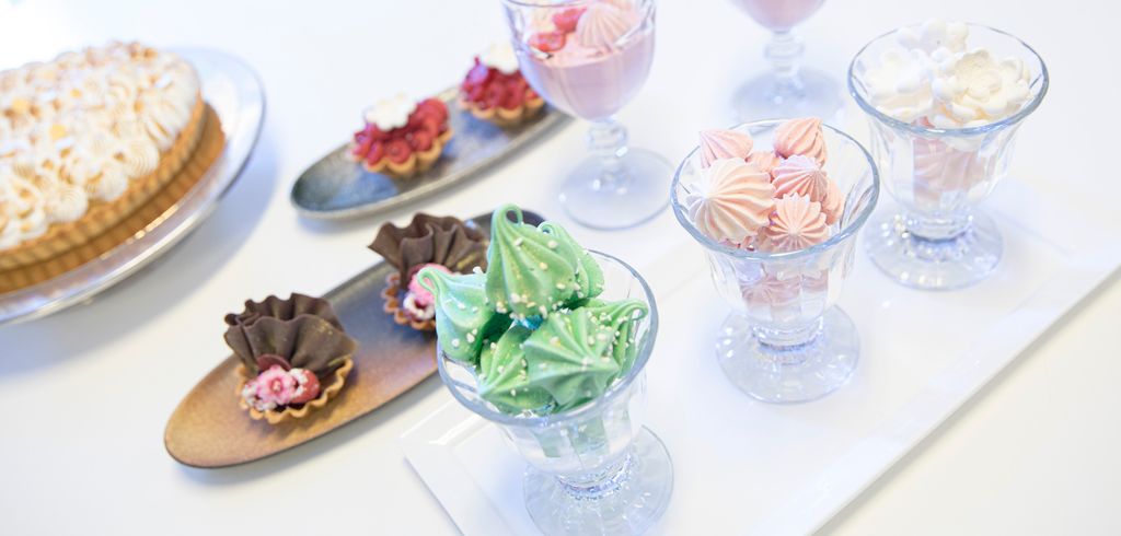 Et bord med ulike desserter som sitronterte, små, fylte terter, pikekyss og bærmousse. Foto.