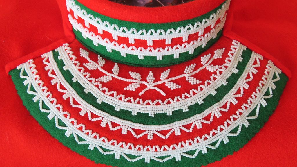 Barmklede i rødt og grønt, dekorert med hvite perler. Foto.