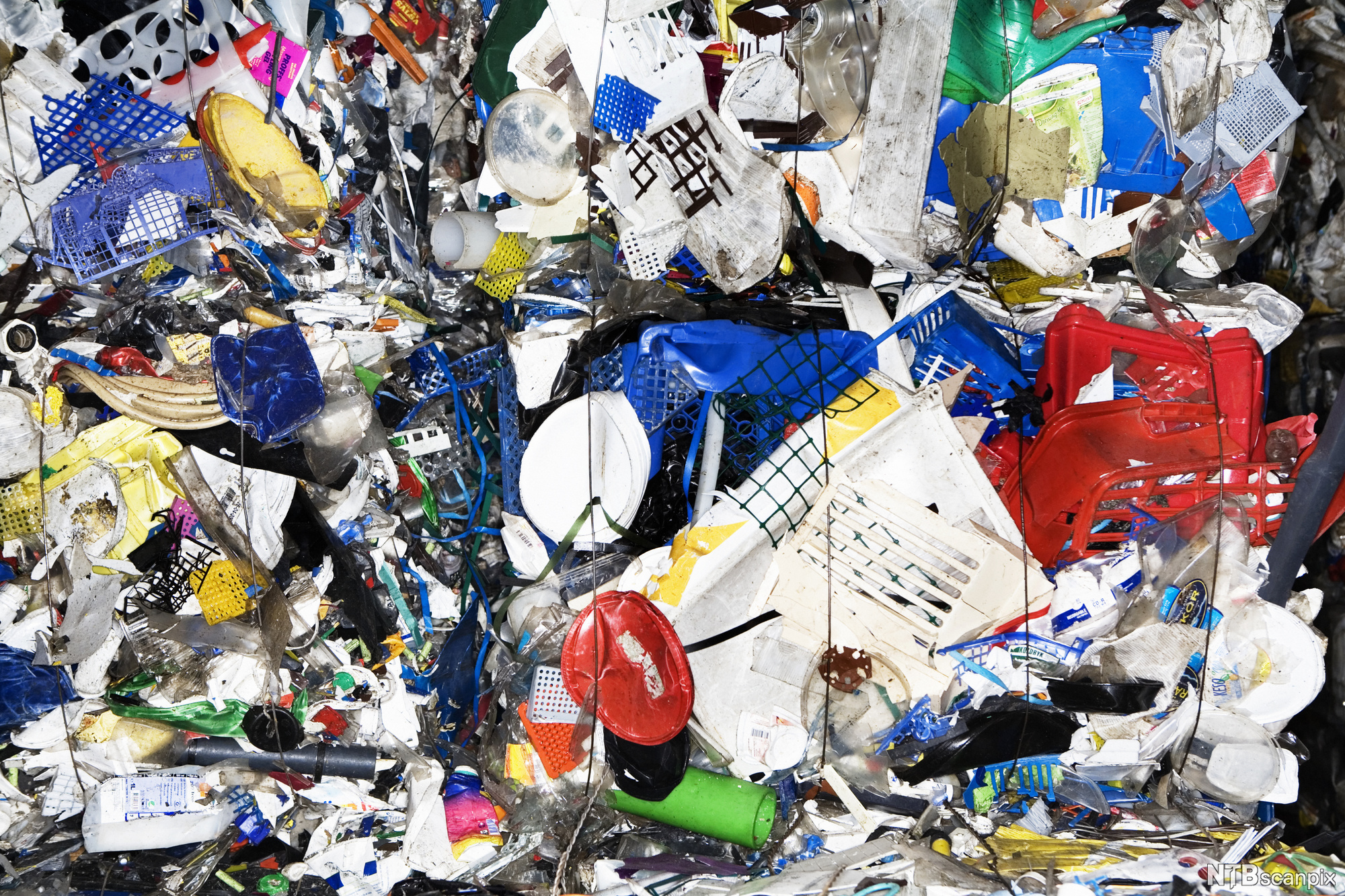 Plastavfall i mange fargar og former pressa saman. Foto.