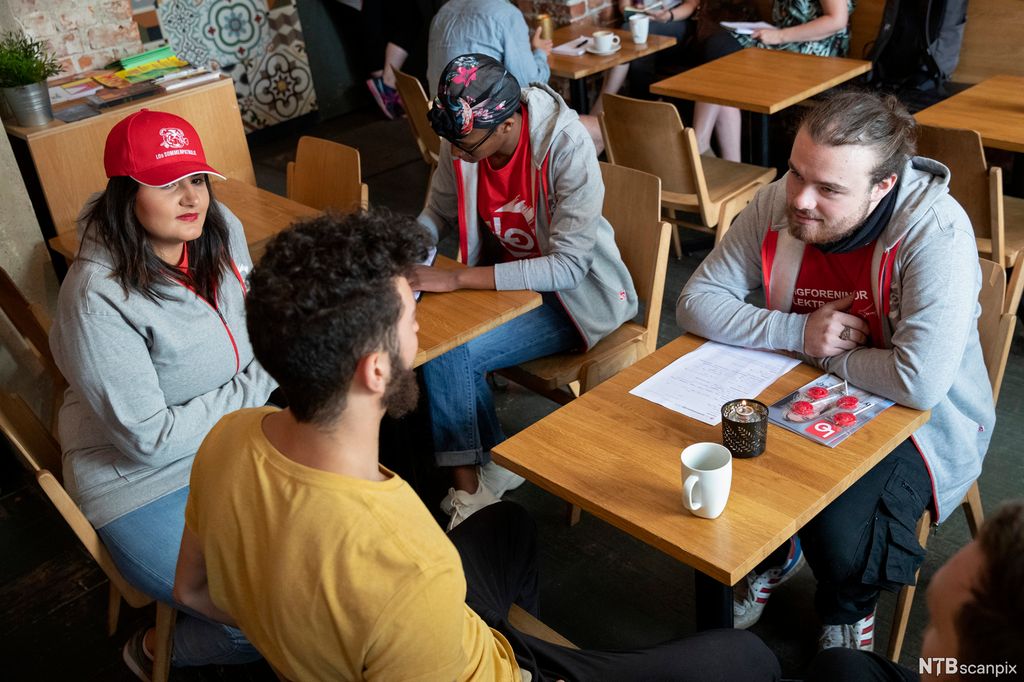 Троє молодих людей домовляються за столом, четвертий - занотовує. Фото.