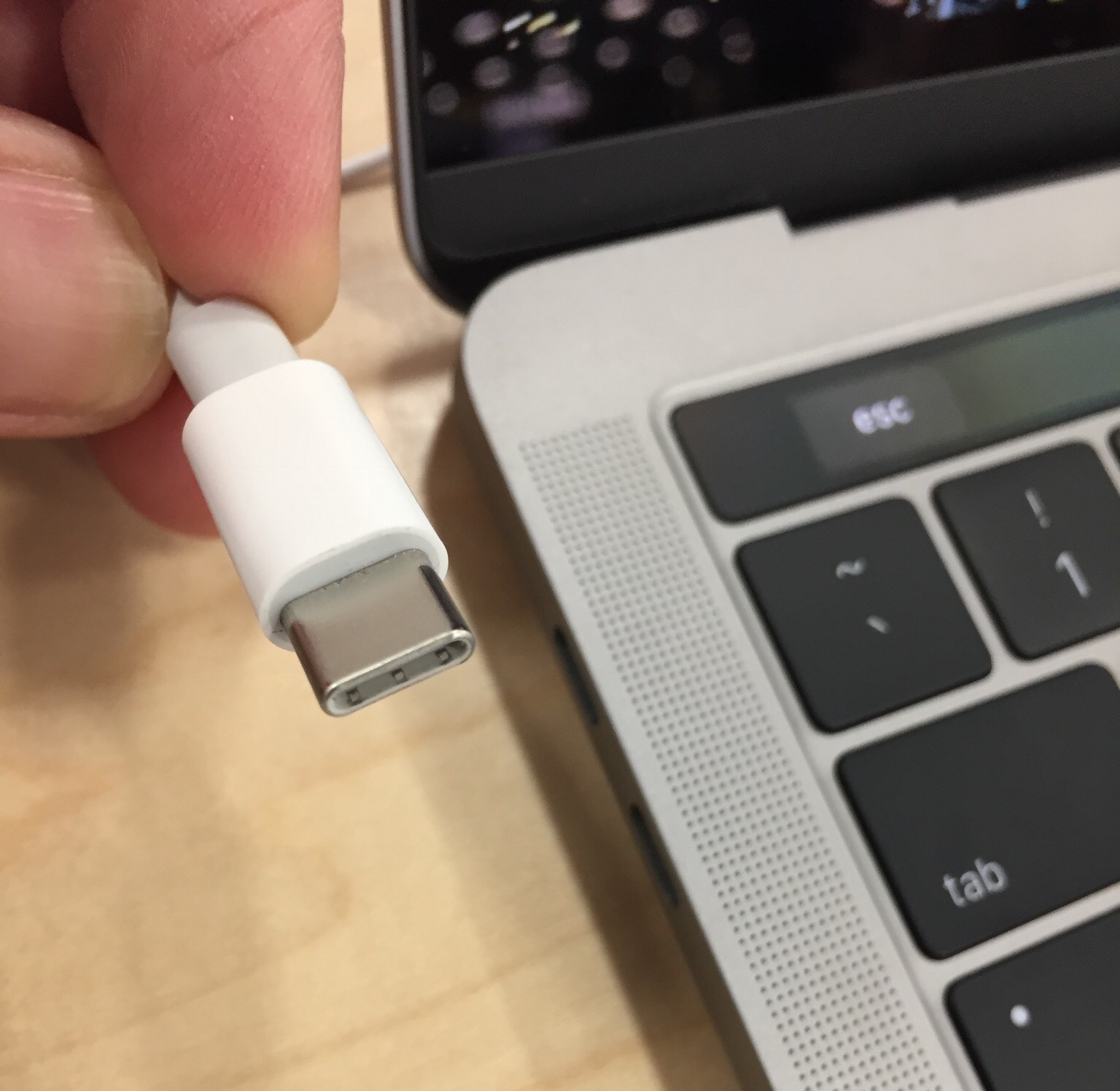 Nærbilde av en hvit USB-C kontakt ved siden av en bærbar datamaskin. Foto
