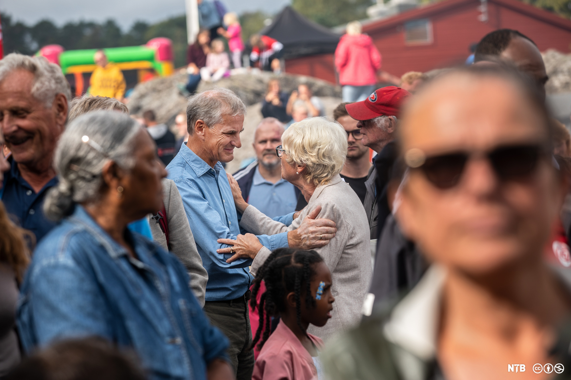 Partileder Jonas Gahr Støre i nær dialog med eldre kvinne midt i en folkemengde. Foto.