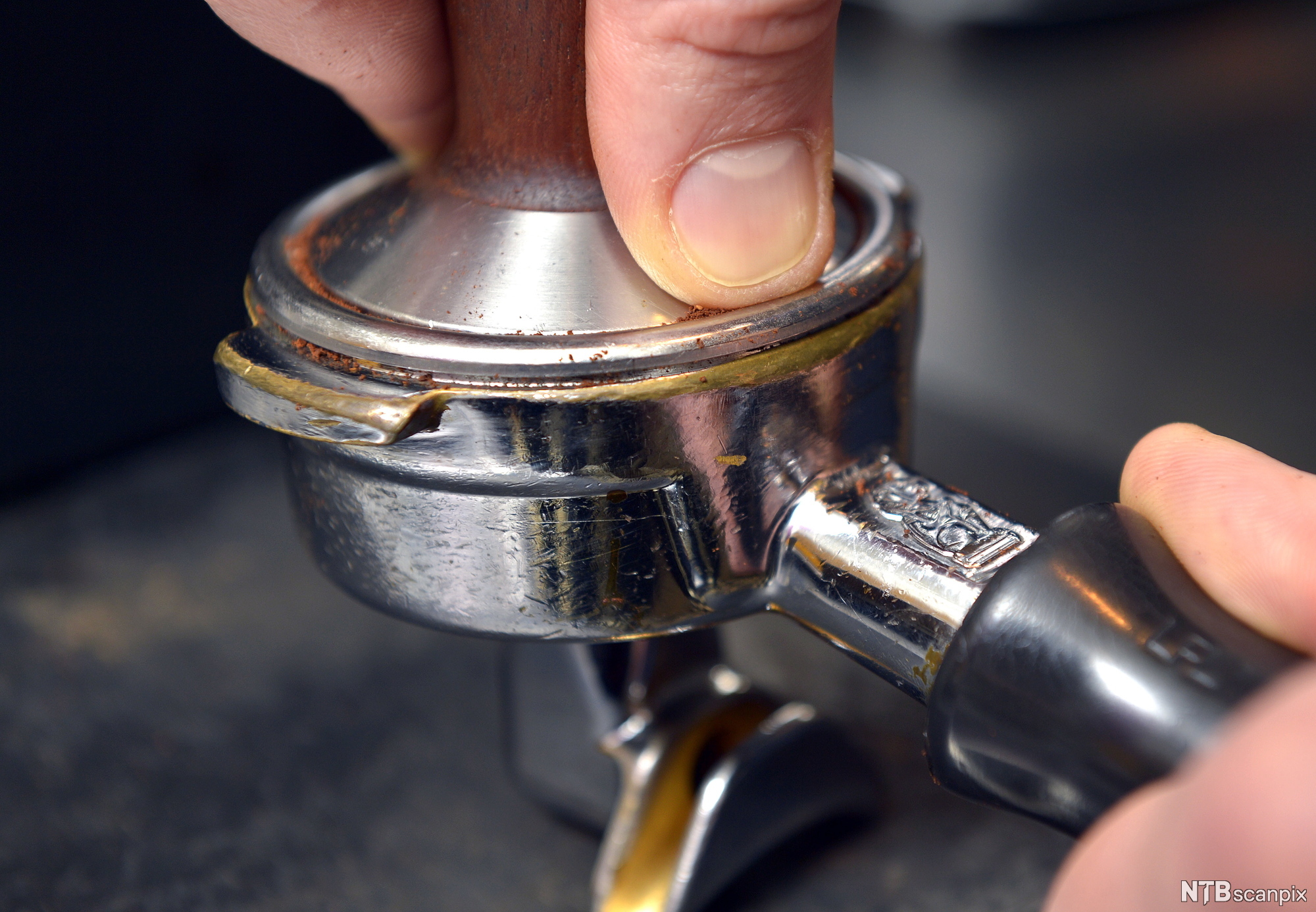 To hender presser sammen kaffe i en filterholder. Foto.