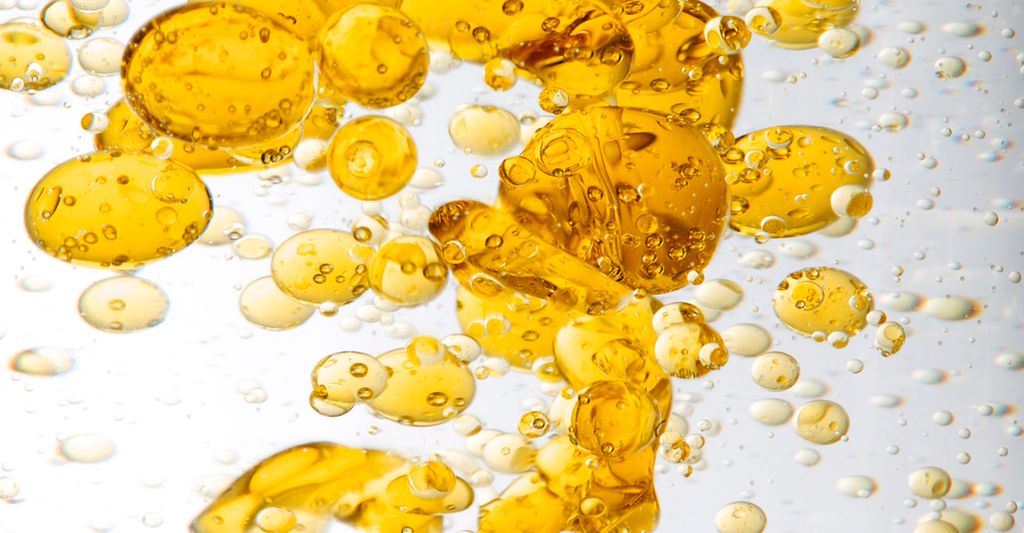 Oransje oljedråper i vann. Foto.