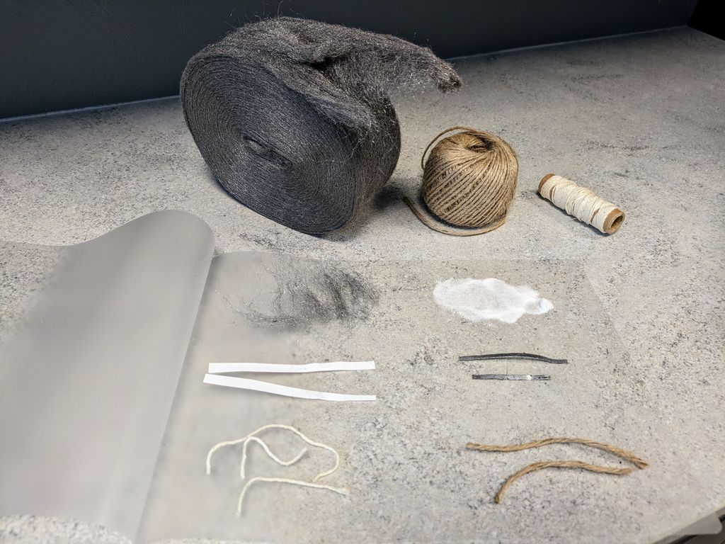 Ulike materialer ligger på et lamineringsark. Materialene er stålull, sukker, papir, magnesium, hyssing og sisalgarn. Foto.