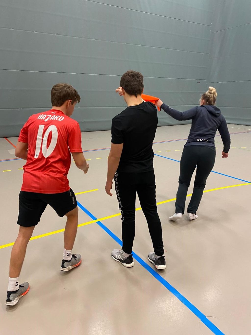 Tre ungdommar i aktivitet i gymsal. Foto.