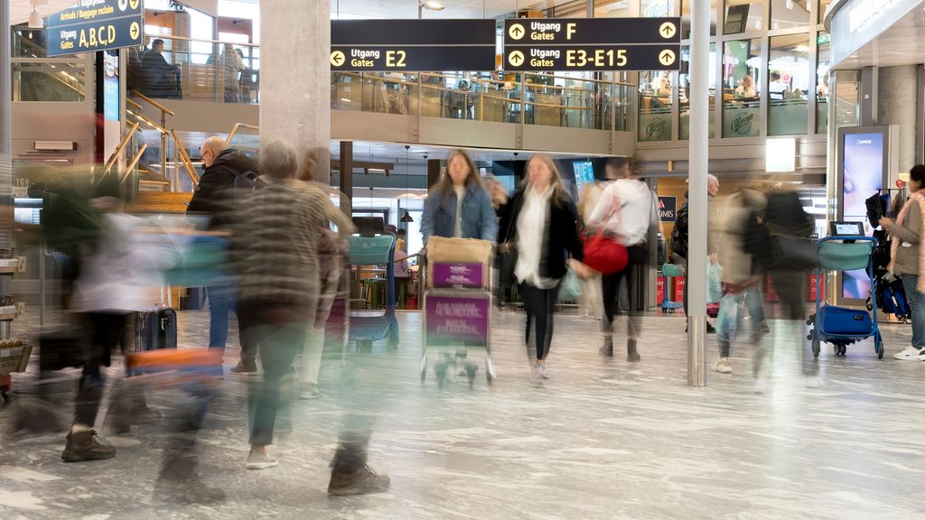 Reisende på en norsk flyplass. Personene som beveger seg, er uskarpe. Foto.