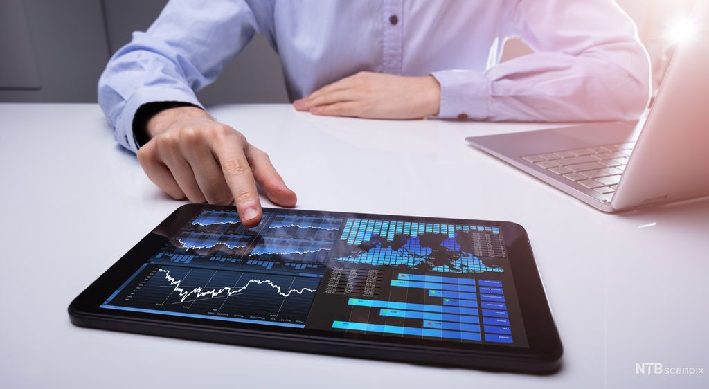 En person som ser på et nettbrett med ulike grafer. Foto.