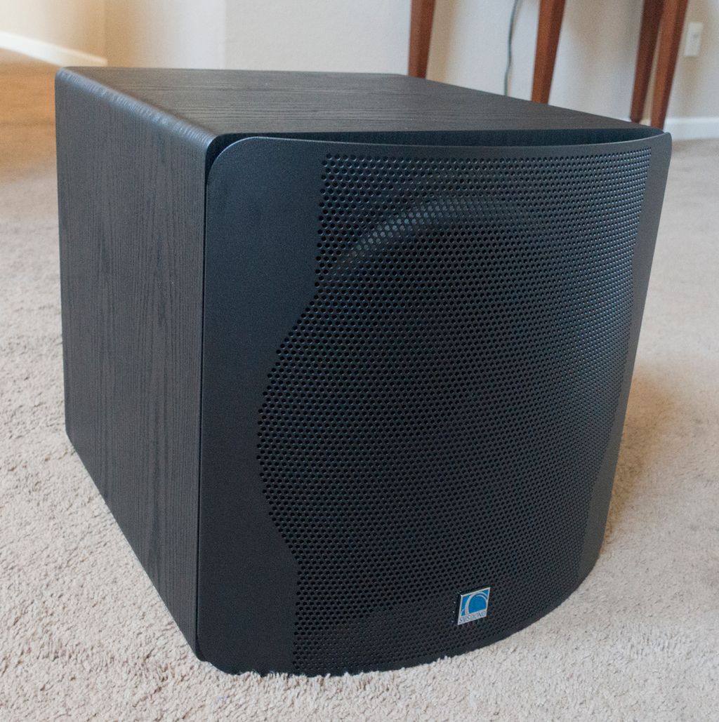En hjemmekinosubwoofer på et teppe i en stue. Foto.