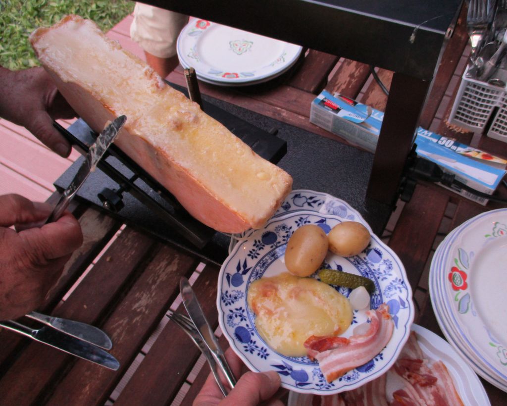 Et raclette-måtid. Smeltet ost skrapes av på en tallerken og serveres med potet, sylteagurk, sølvløk og bacon. Foto.