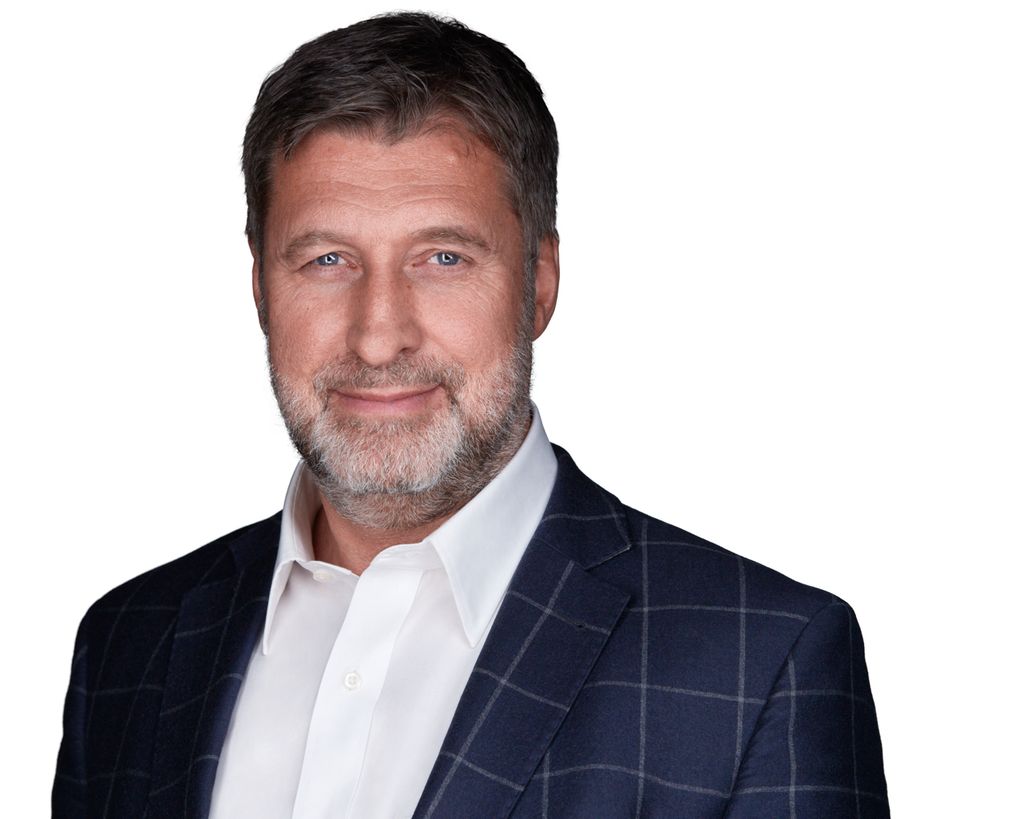 Mann med kort skjegg, blå jakke og hvit skjorte. Foto.