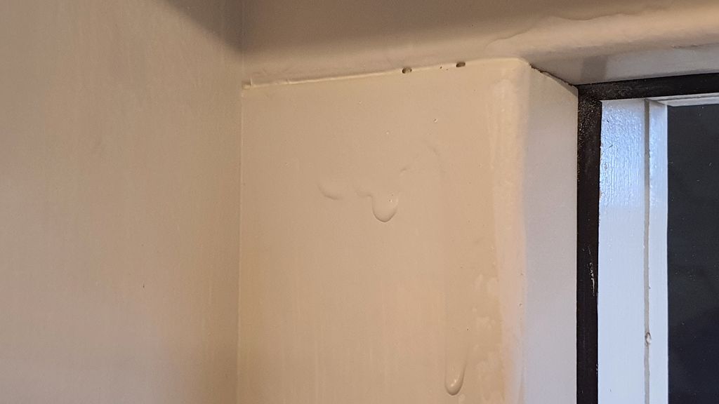 Måling i tjukt lag sig nedover veggen. Bilde.