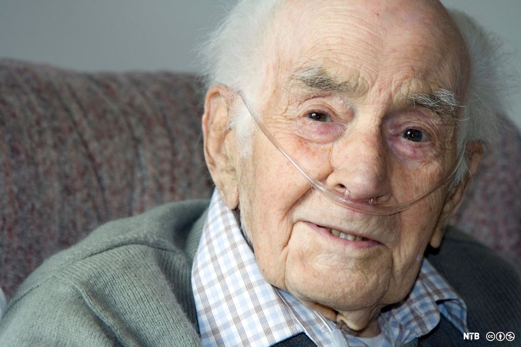 Eldre mann får oksygen tilført via en slange i nesa. Foto.