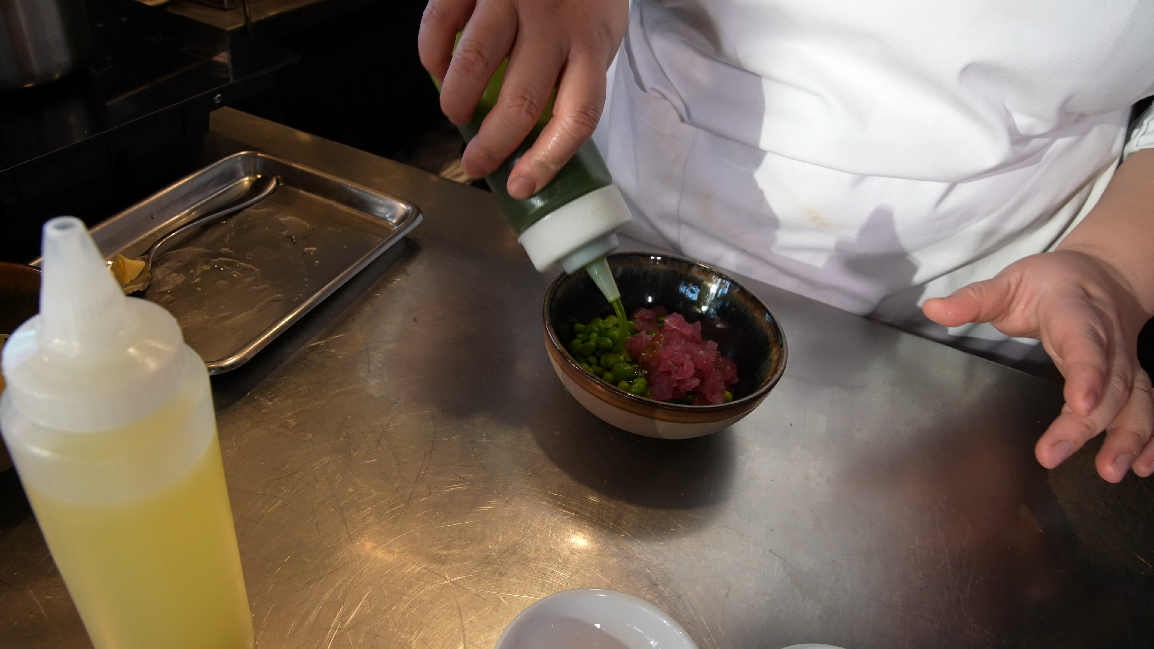 Urteolje helles over erter og syltet rødløk i en skål. Foto.