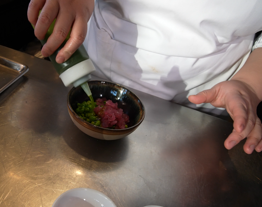 Urteolje helles over erter og syltet rødløk i en skål. Foto.