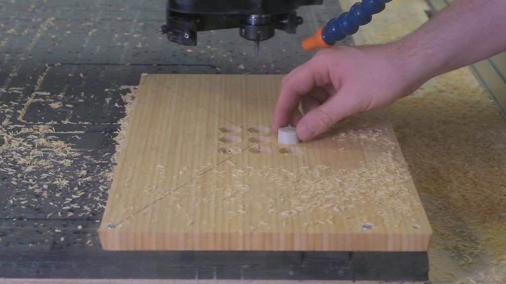 Prøving av ei steinbrikke i et utfrest hull på et bambusbrett. Foto.