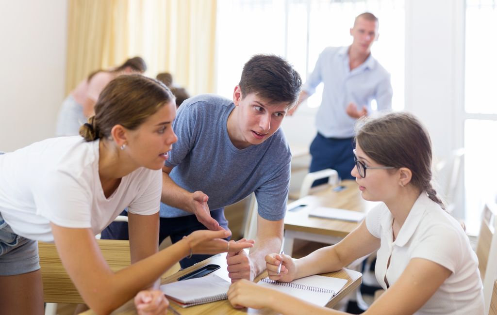 Tre elever diskuterer. Foto.