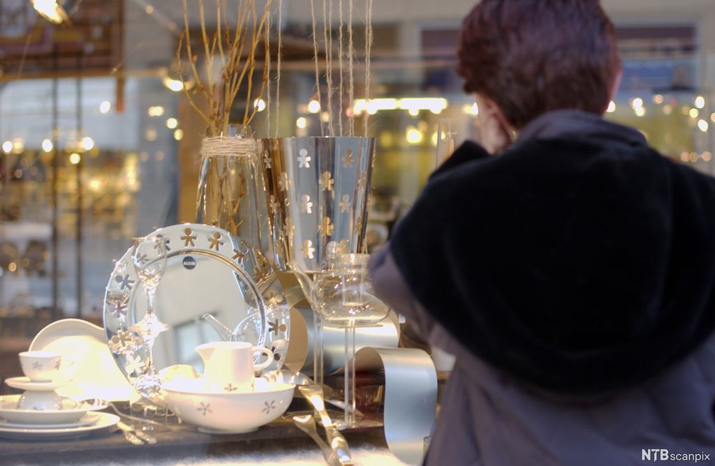 Kvinne ser på servise i et utstillingsvindu. Foto.