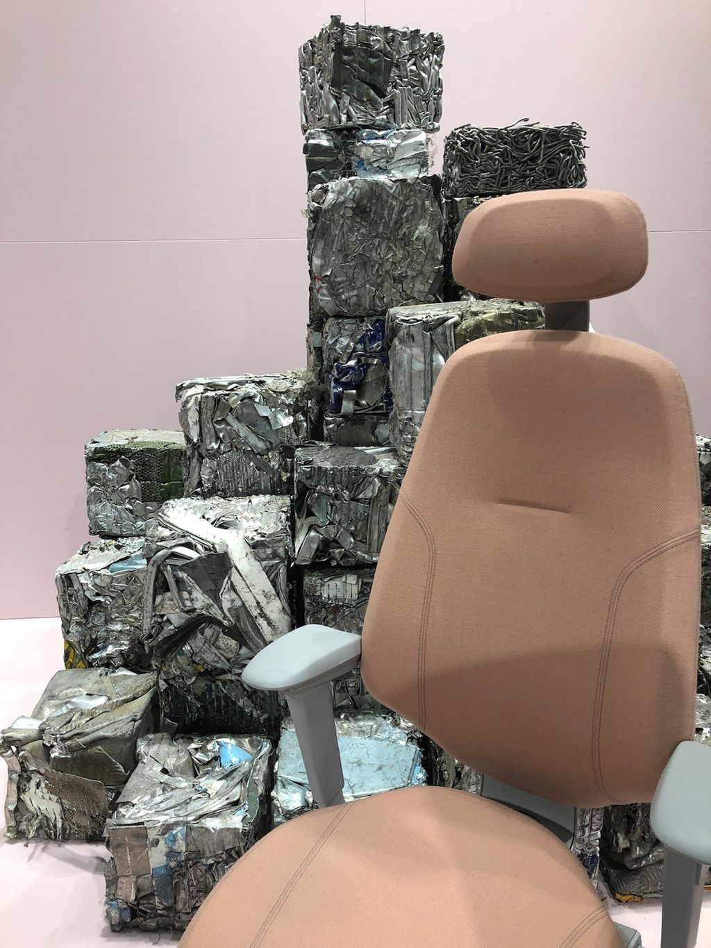 En kontorstol foran stabler av gjenvunnet aluminium. Foto.