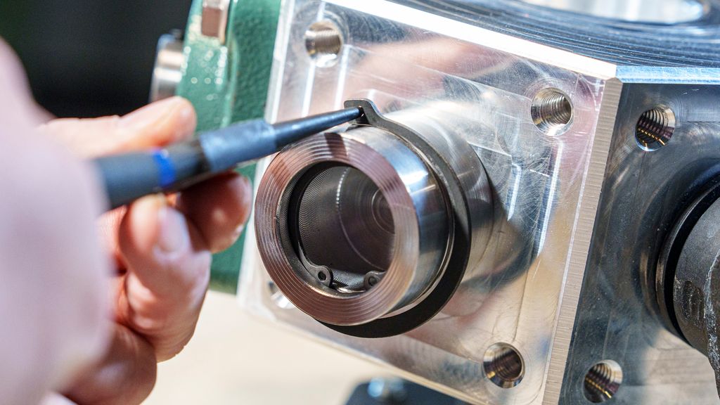 Ei tang setter en ring på plass i et spor på en aksling. Foto.