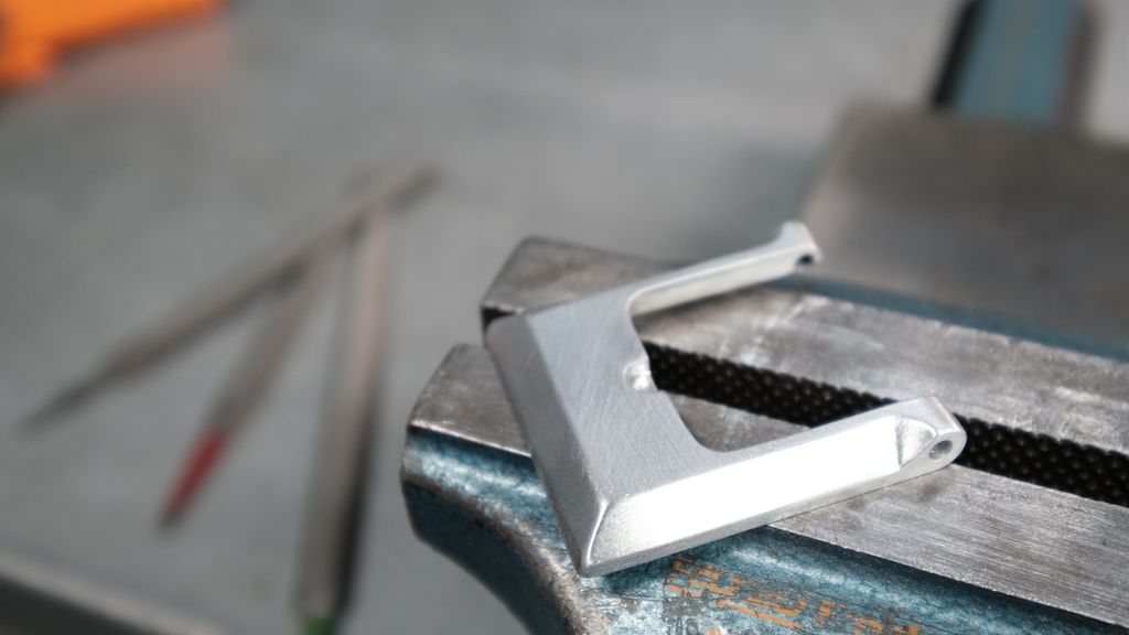 Aluminiumsdel forma som en spiss U ligger på et arbeidsbord. Foto.