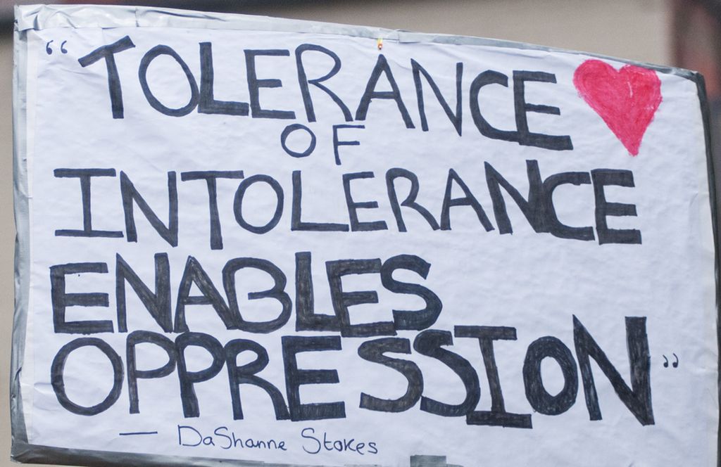 People holding a sign saying "Tolerance of intolerance enables oppression". Photo.