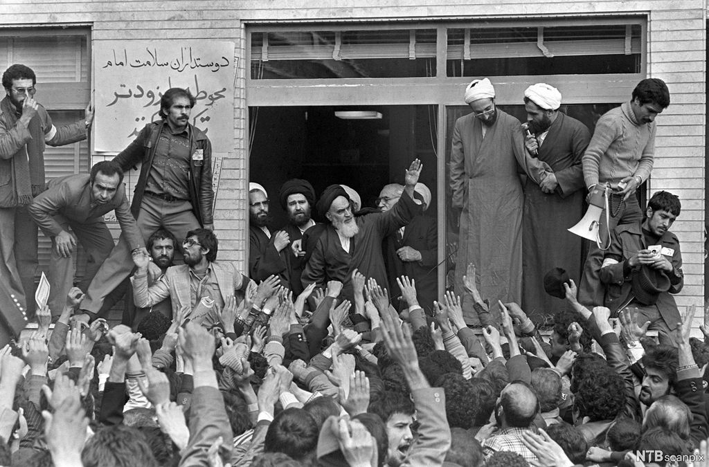 Mann med skjegg og turban hilser til folkemengde. Foto.