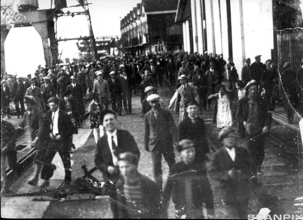 Mange mennesker samlet i et industriområde. Svart-hvitt foto.