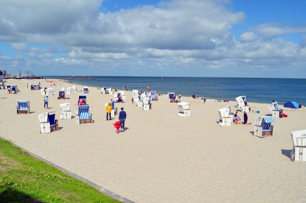 Badestrand på øya Sylt i Nord-Tyskland. Det er ei sandstrand med mange strandkurver der folk kan sitte og sole seg i ly av vinden. Det er rolig på havet, og været er fint.  Foto.