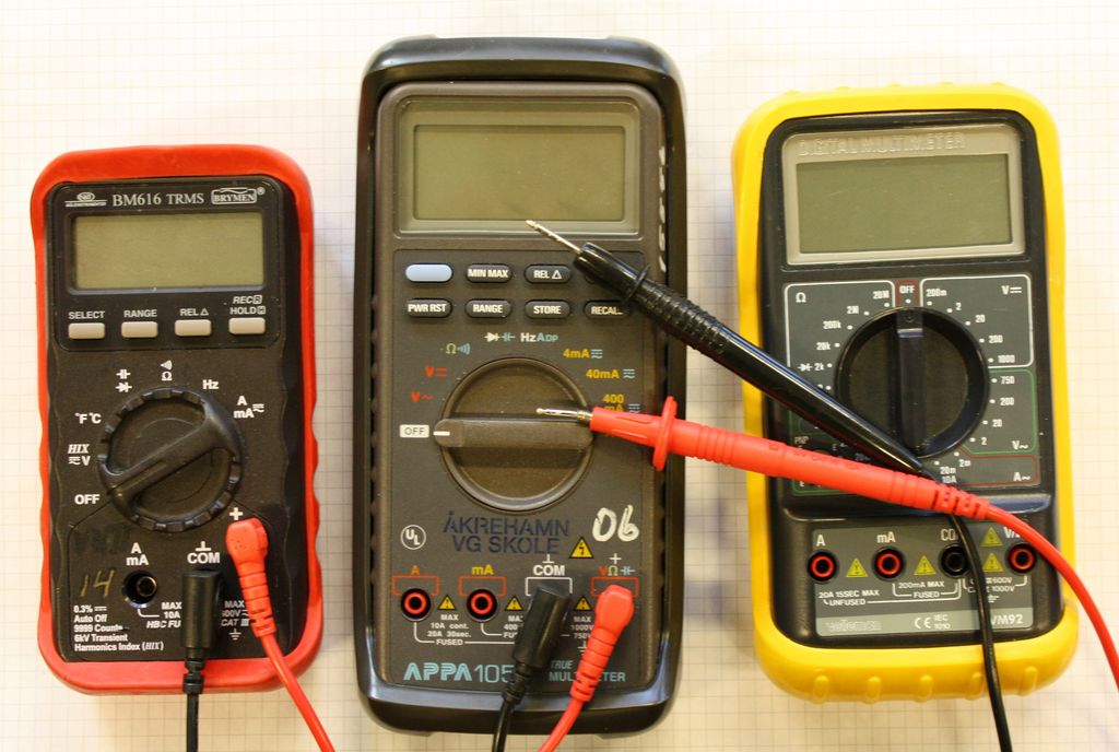 Tre multimetere, det vil si måleverktøy for elektrisitet, med ledninger, knapper og skjerm. Foto.