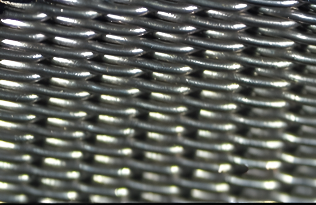 Filterduk. Ståltråd som er voven over tverrgåande ståltrådar dannar eit rutenett. Hola mellom trådane er opningar som slepp fast stoff, væske eller gass gjennom filteret. Foto.