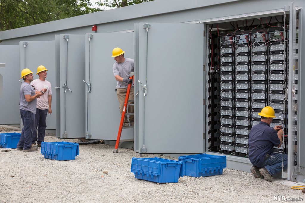 Muntre arbeidere vedlikeholder batteribanker. Foto.