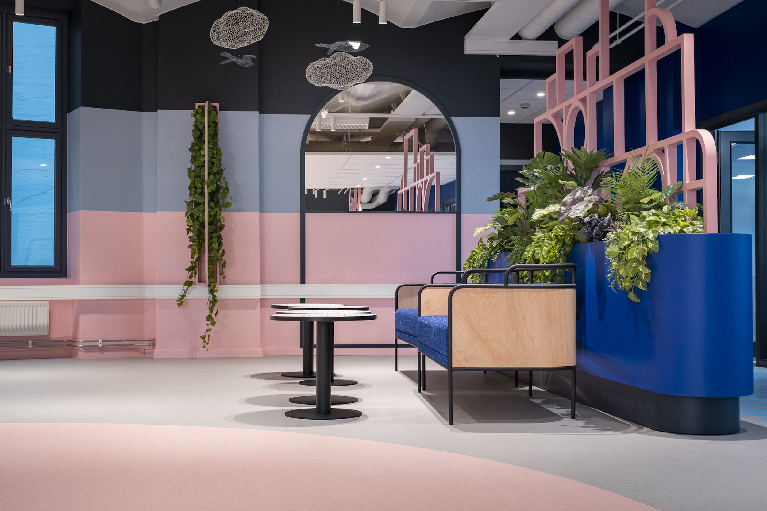 Sittegruppe i ei kantine der veggen og gulvbelegget er delt i rosa og grå flater. Foto.