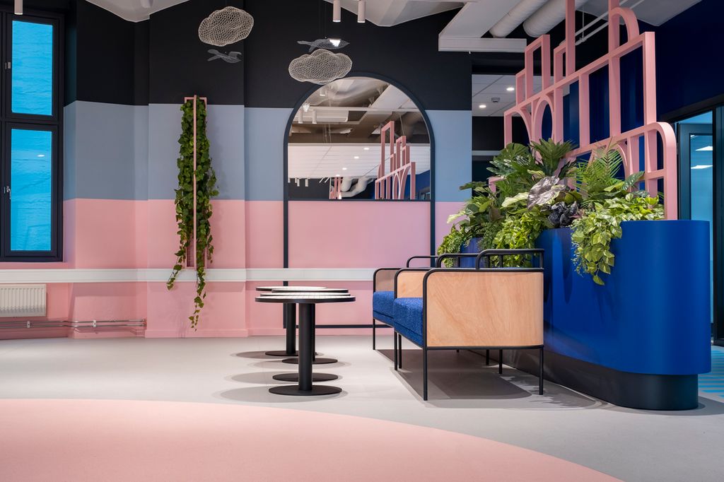 Sittegruppe i ei kantine der veggen og gulvbelegget er delt i rosa og grå flater. Foto.