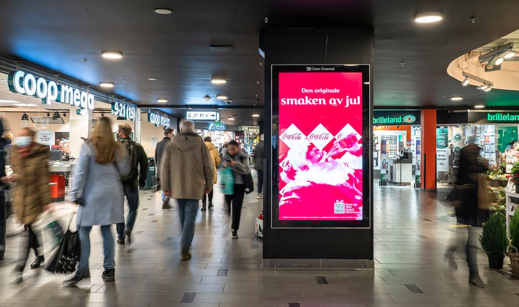 Fotografi av menneske som går mellom lyssette skilt på eit kjøpesenter.