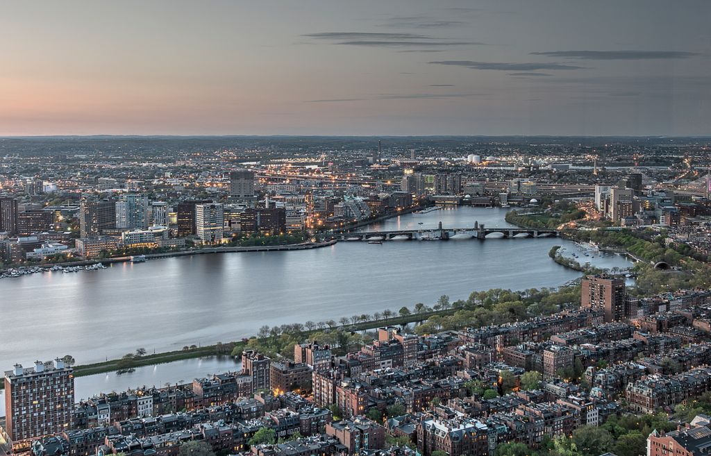 View of the city of Boston, Massachusetts, USA. We see a river with houses on both sides. The sky is slightly pink. Photo.