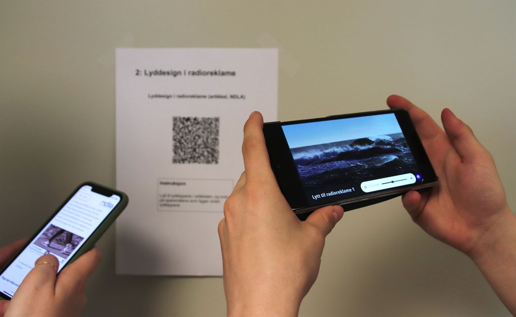 To par hender holder hver sin mobil som har skannet en QR-kode. Foto.
