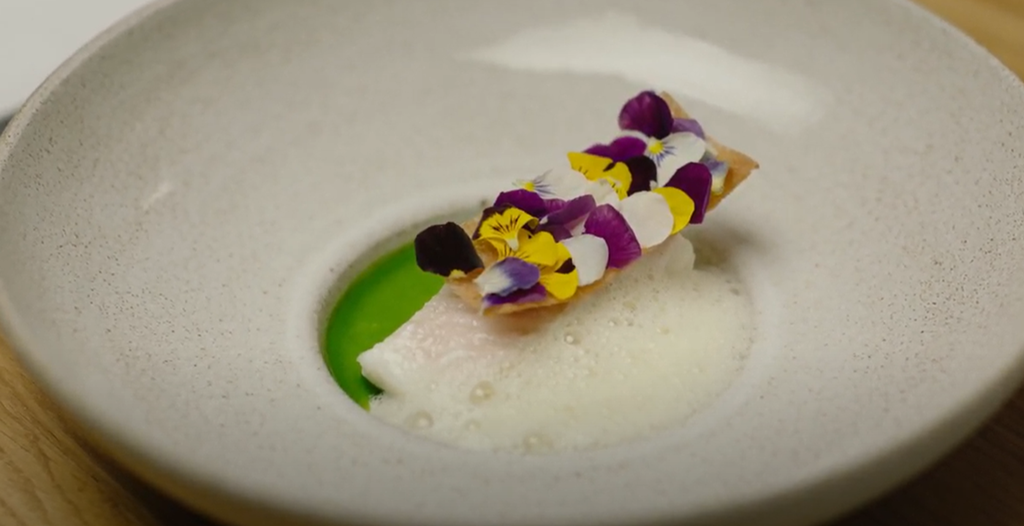 Kveite med gressløkolje anrettet med blomster. Foto.