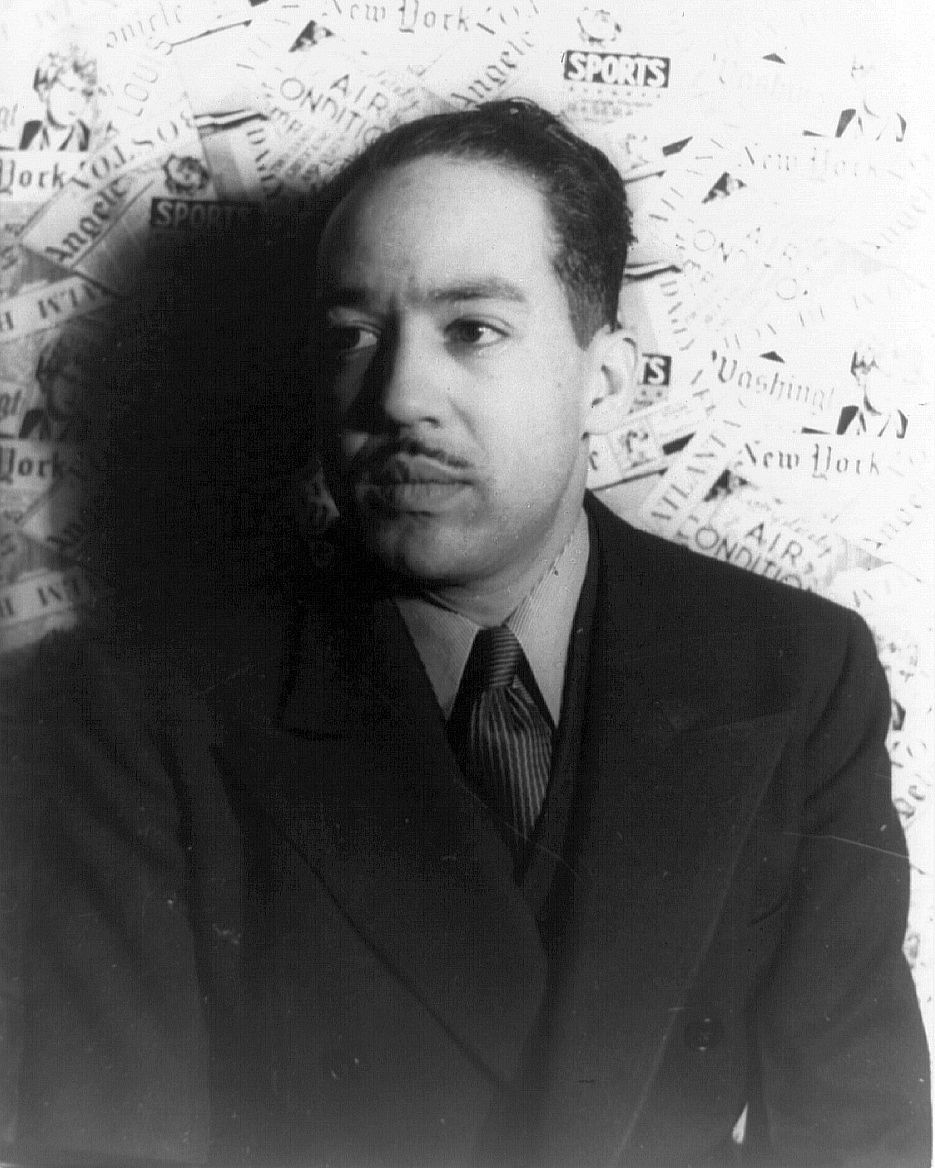 Photo: Langston Hughes is a middle aged man. He is wearing a suit. He has a thin moustach. 
