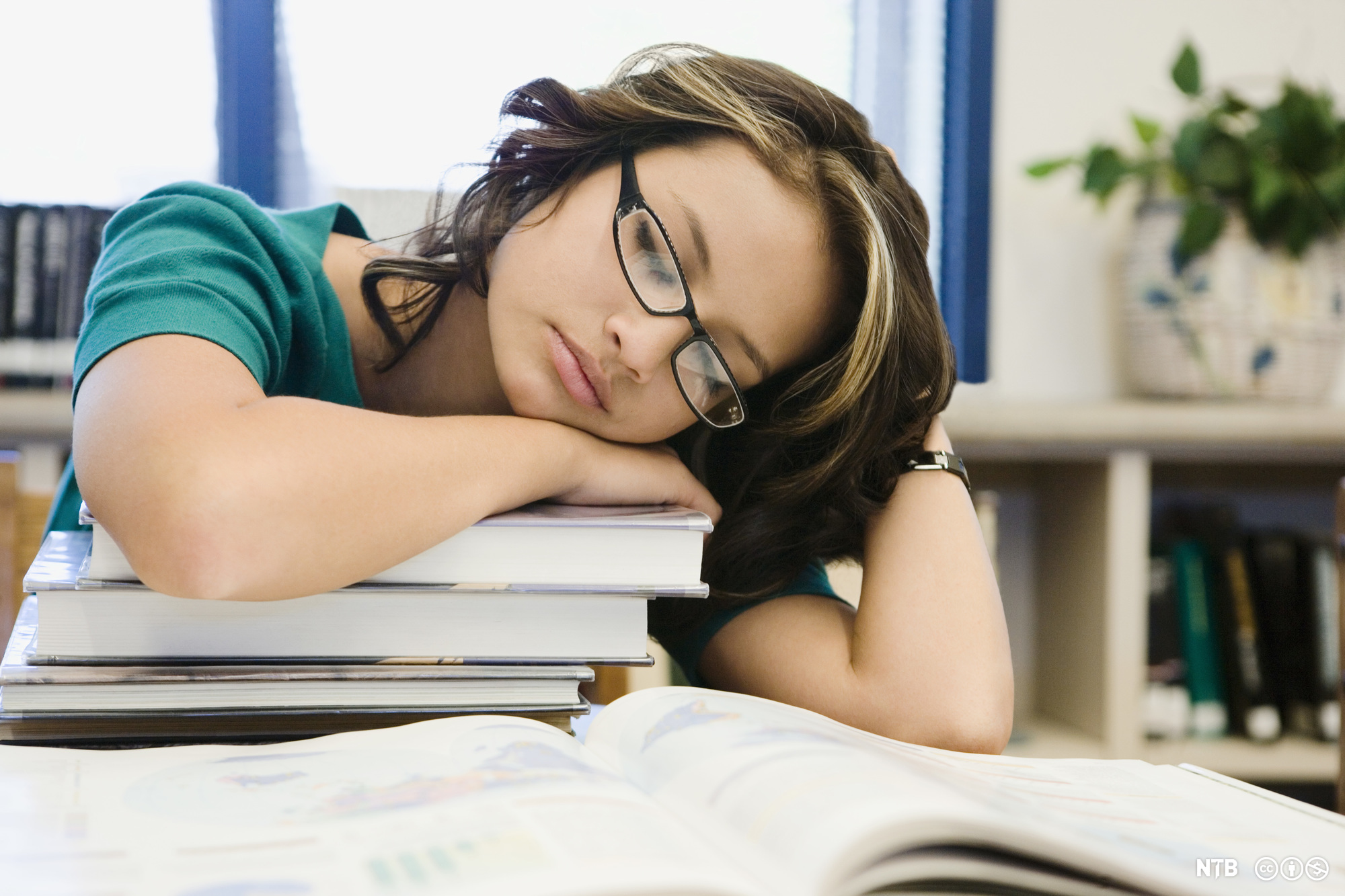 Teenage student sleeping over her books. Photo.