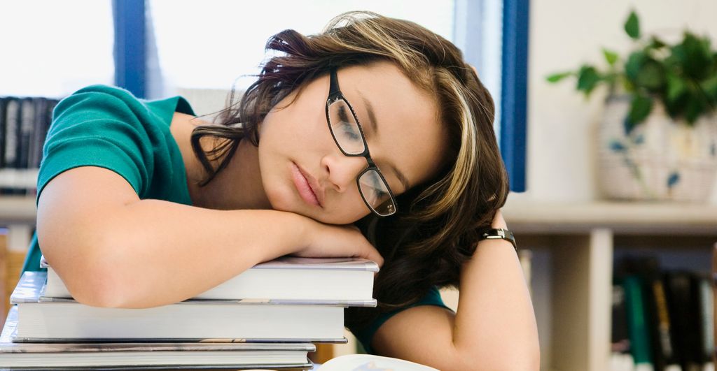 Teenage student sleeping over her books. Photo.