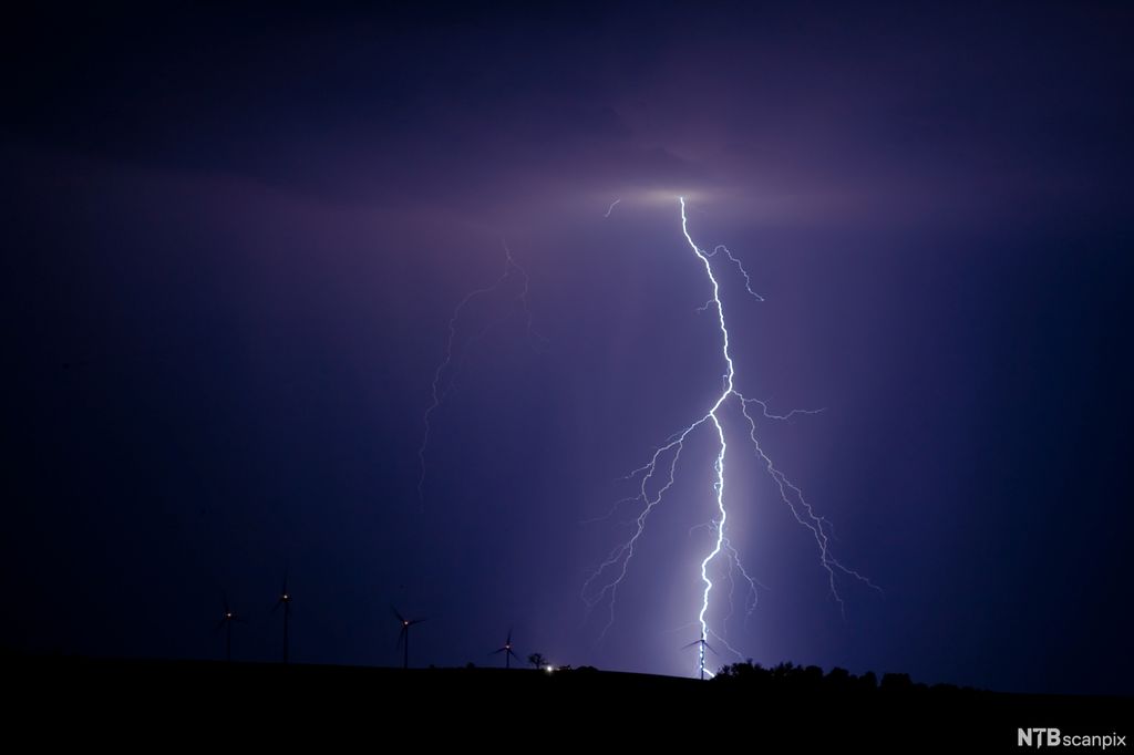 Kvitt tynt lynnedslag som går fra himmel til bakken på ein mørk kveld. Foto