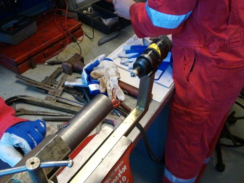 To personer i arbeidsklær med utstyr som skal kjøres i brønnen. Foto.