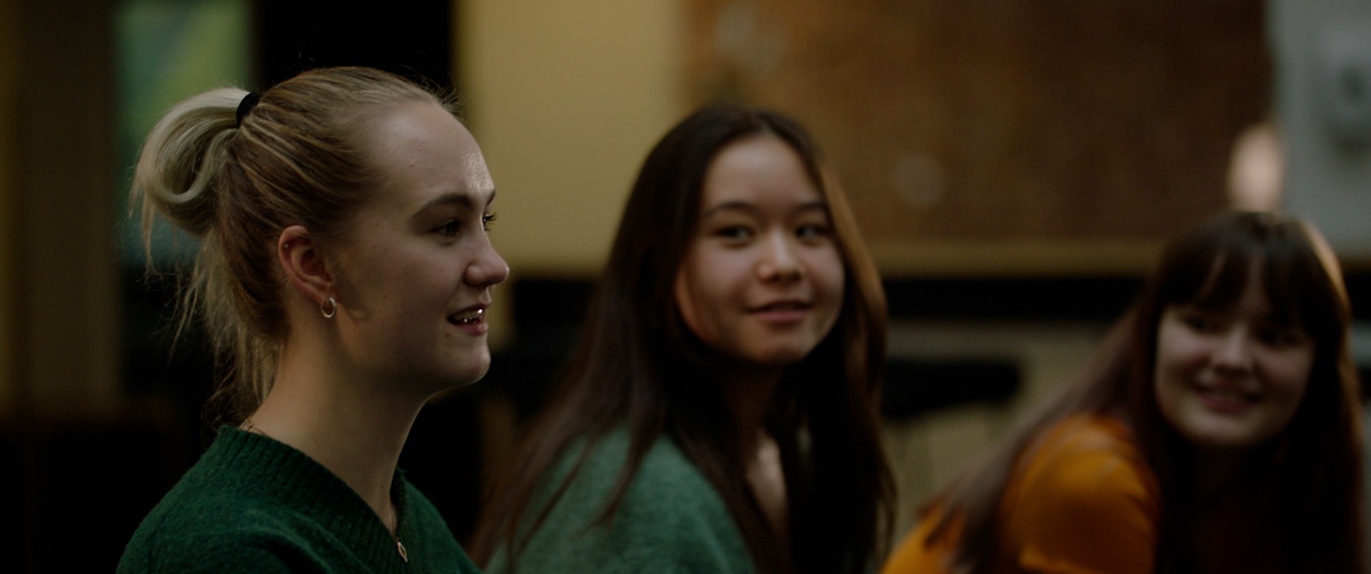 Tre blide ungdommer sitter sammen og snakker. Foto